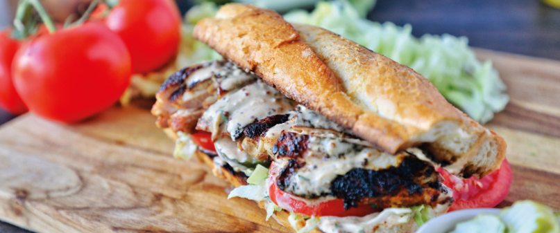 Blackened Chicken Po' Boy with remoulade, tomatoes, and lettuce on a toasted French roll