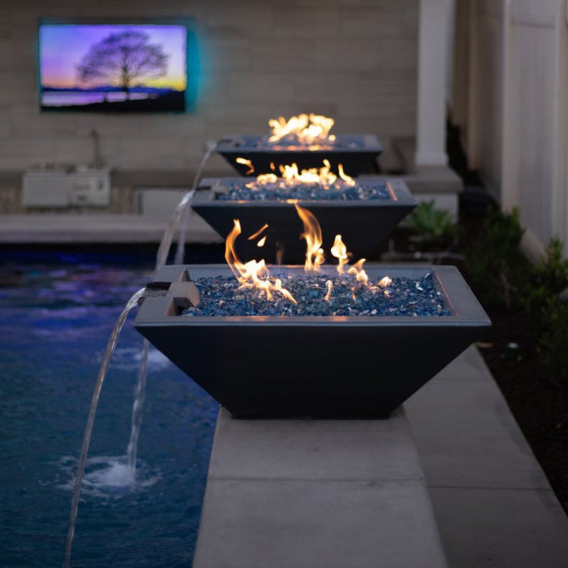 Outdoor fire pit with flames and water feature near a pool