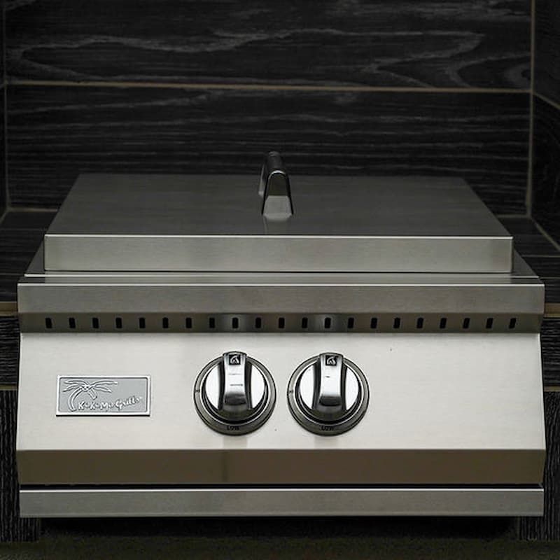 Stainless steel grill with two knobs on a dark tiled wall background