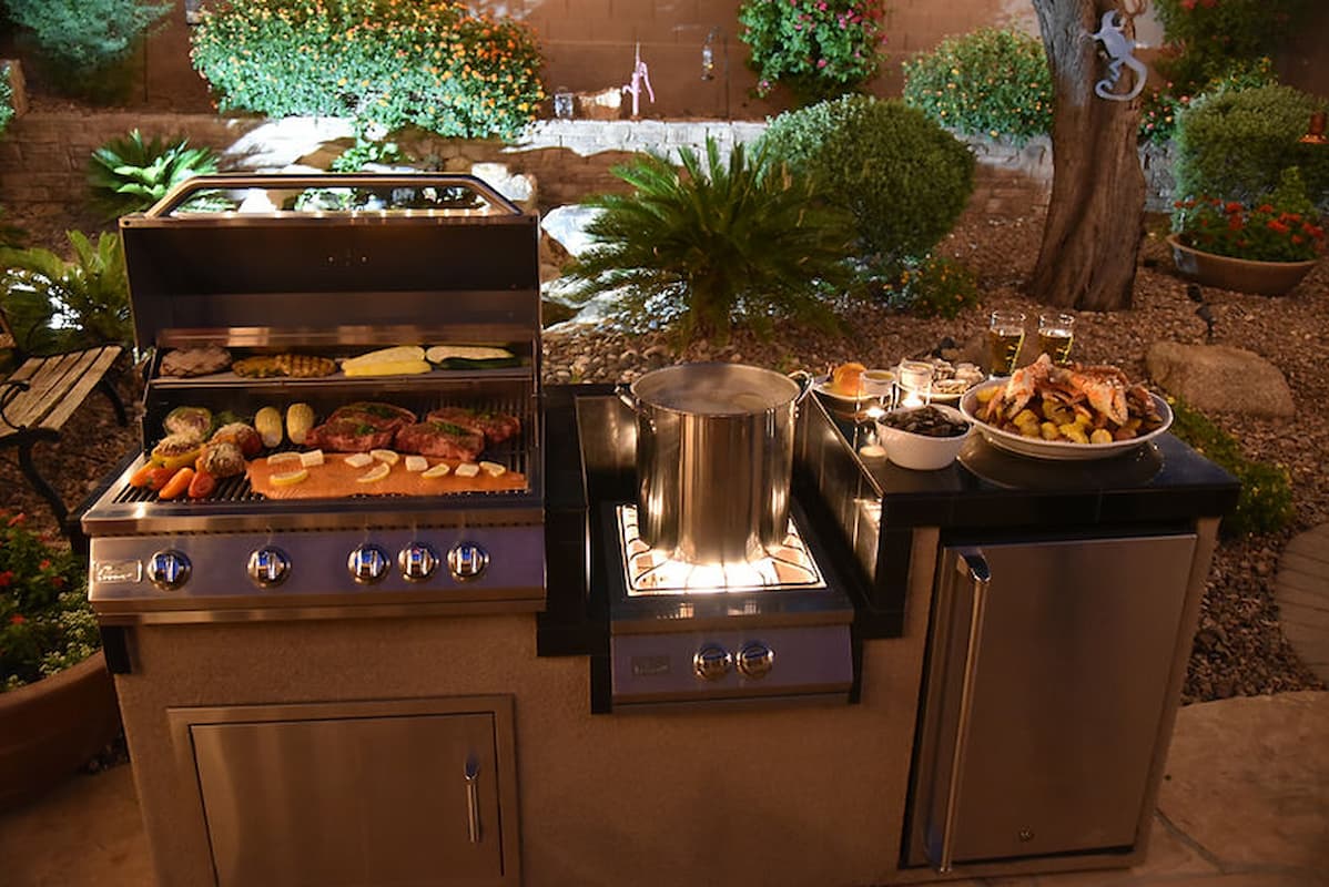 Outdoor kitchen setup with grills and cooking equipment in a garden setting