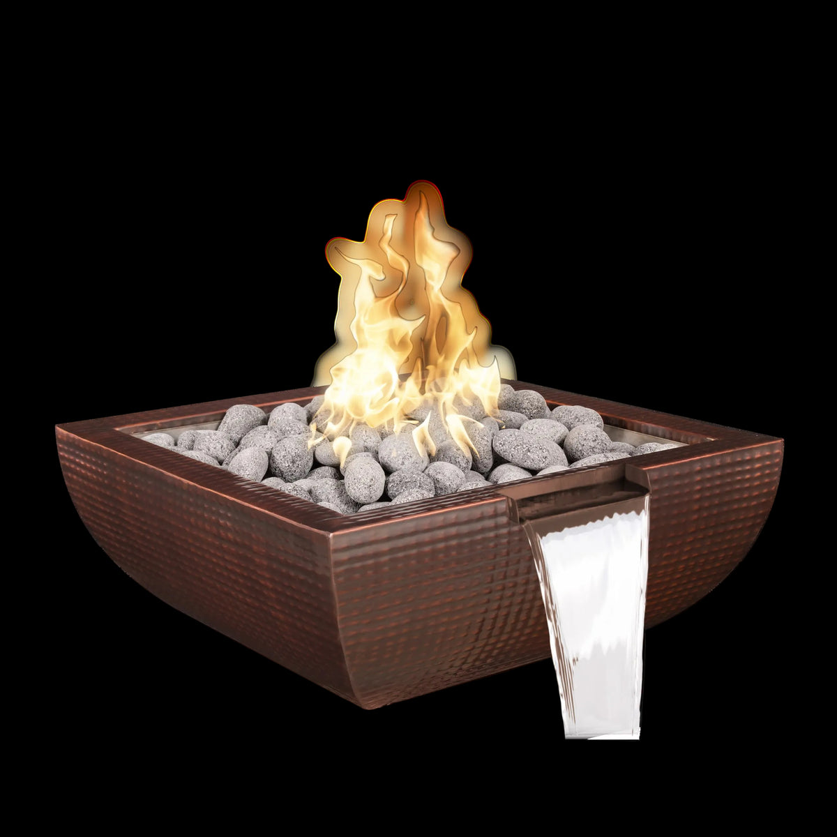A square outdoor fire pit with a hammered metallic bronze finish, filled with gray river rocks and glowing orange flames, with a waterfall spout pouring clear water. The product is shown against a solid black background.