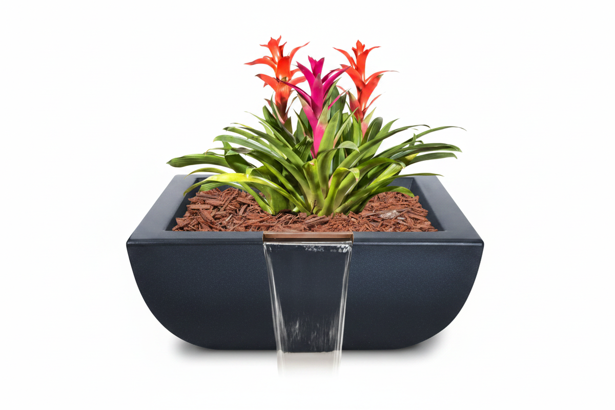 A modern black rectangular planter with a front waterfall feature, filled with brown mulch and green foliage with bright orange and pink flowers, isolated on a white background.