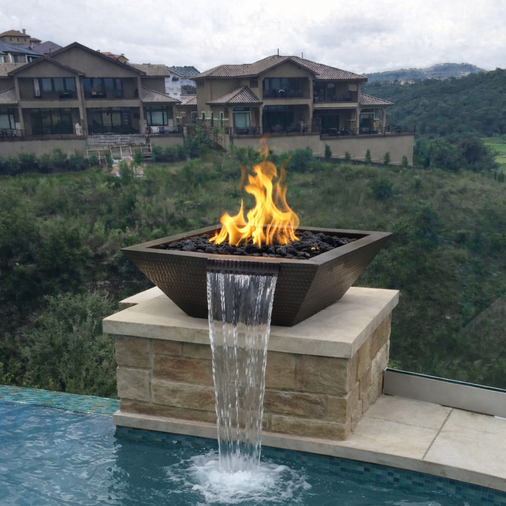 Outdoor fire pit with water feature by a pool, surrounded by greenery and houses.