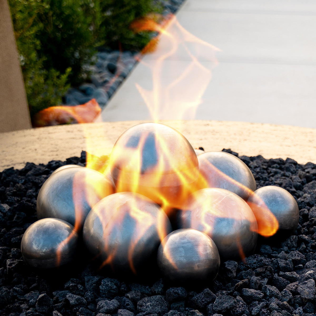 Steel fire balls displayed together on lava rock with flames; sold individually