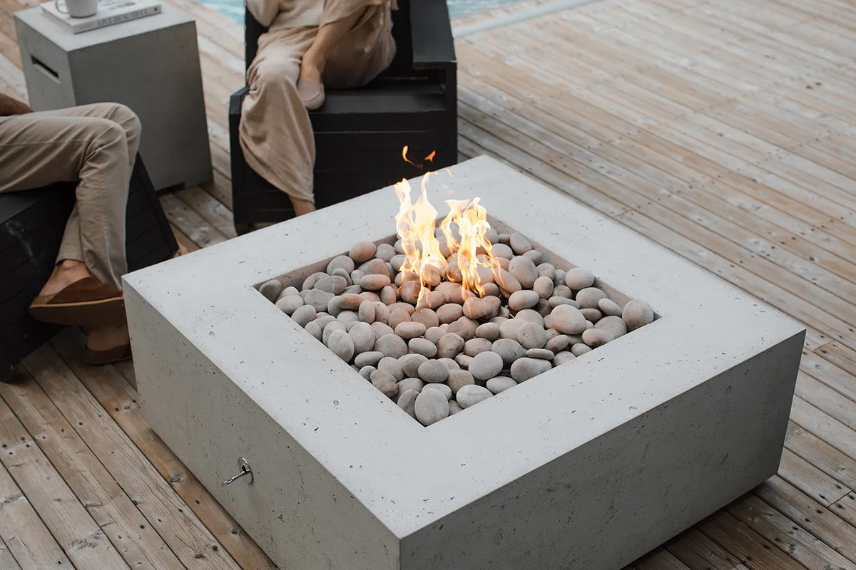 Concrete fire pit with flames on a wooden deck