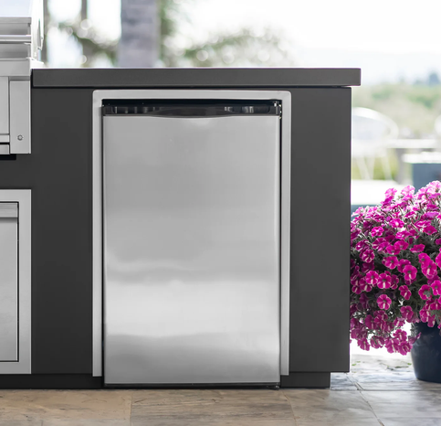 Stainless steel outdoor refrigerator on a patio with flowers in the background