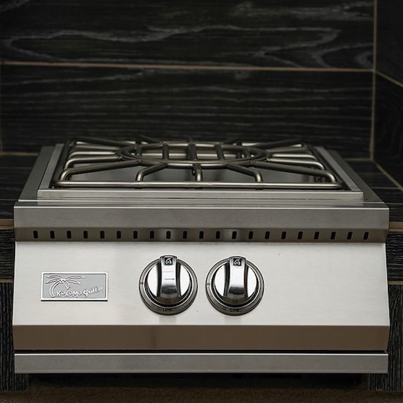A stainless steel outdoor gas grill insert with two control knobs and a gas grate top, set against a dark wood-look tiled background.