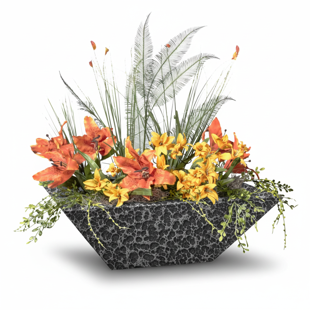 A modern geometric planter with a dark gray and black crackle stone texture, filled with vibrant orange lilies, yellow flowers, and green ornamental grasses, set against a plain white background.