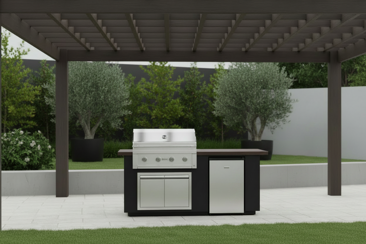 A stainless steel and black outdoor kitchen island set under a covered patio, featuring a built-in grill, storage cabinets, and a side refrigerator, with greenery in the background.