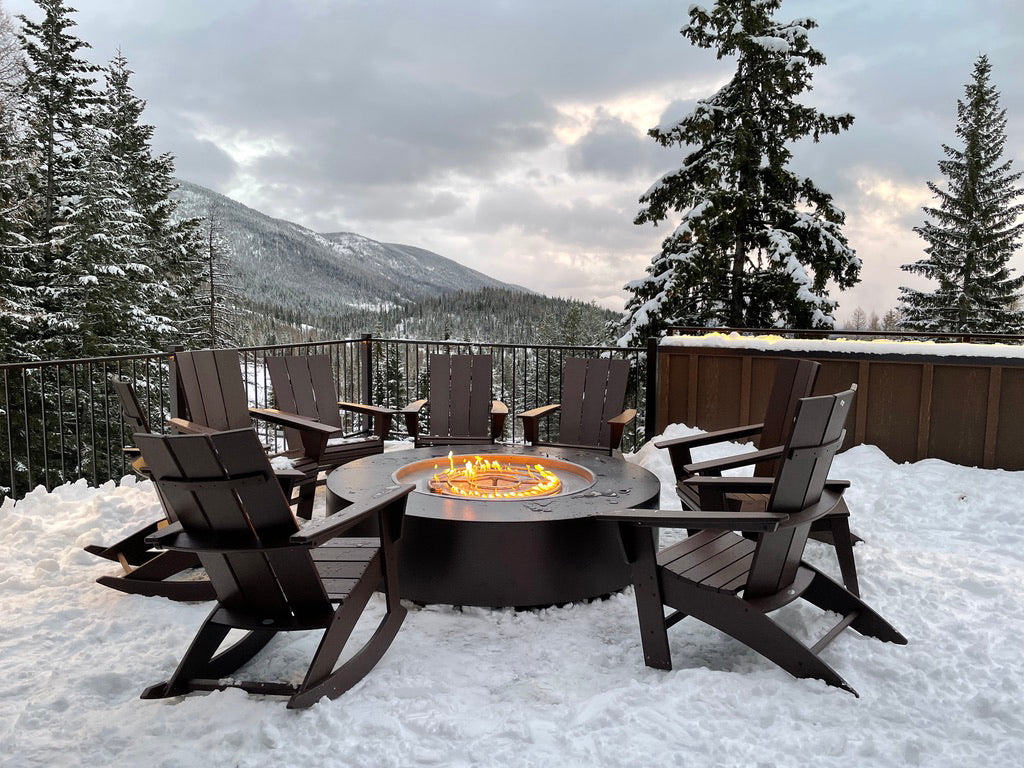 Fire pit table with chairs on a snowy deck with mountain view