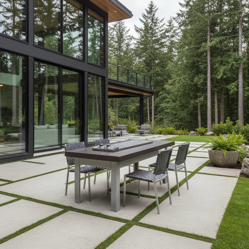Modern outdoor patio with a dining table and chairs in front of a glass house.